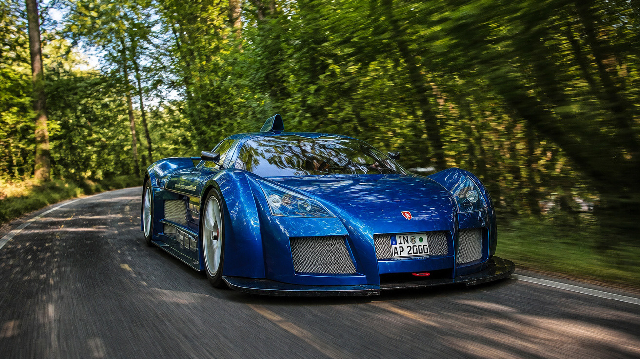 Carro desportivo azul a alta velocidade numa estrada rodeada por árvores verdes.
