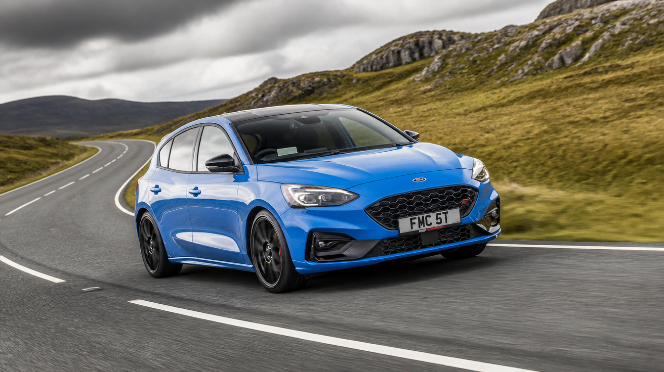 Carro desportivo azul a circular numa estrada sinuosa rodeada por colinas e céu nublado.