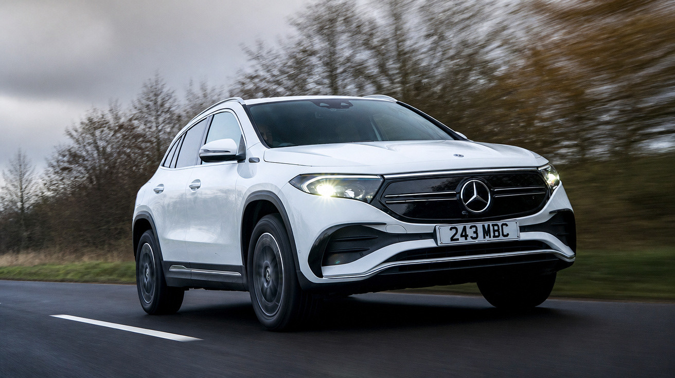 Carro elétrico Mercedes-Benz EQB branco a circular numa estrada com árvores desfocadas ao fundo.